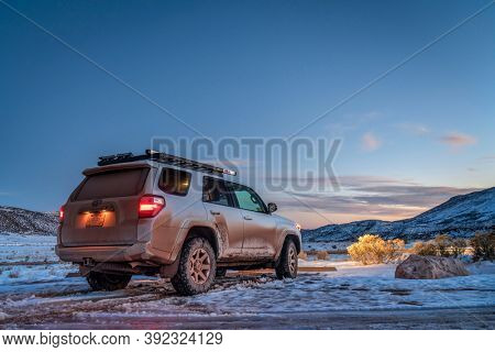 Fort Collins, CO, USA - October 28, 2020: Dirty Toyota 4runner SUV at dusk in Red Mountain Open Space , recreational area at foothills of Rocky Mountains in northern Colorado, fall scenery with snow.