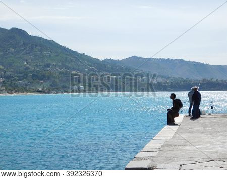 Cefalu, Sicily, Italy. May 10, 2017. Two Men Fishing In The Harvor Of Cefalu