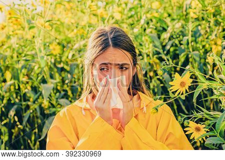 Beautiful Sexy Young Woman Lies On Flowers Background. Young Girl Sneezing And Holding Paper Tissue 