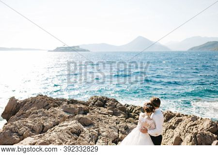 Bride And Groom Are Hugging On The Rocky Beach Of The Mamula Island Near Arza Fortress