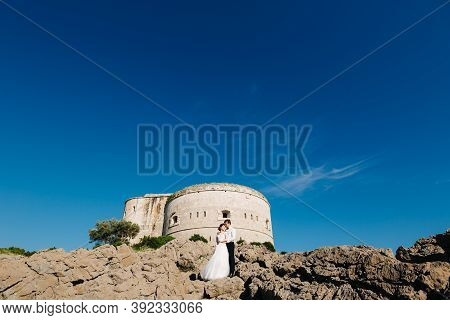 Bride And Groom Are Hugging Near The Arza Fortress On The Mamula Island