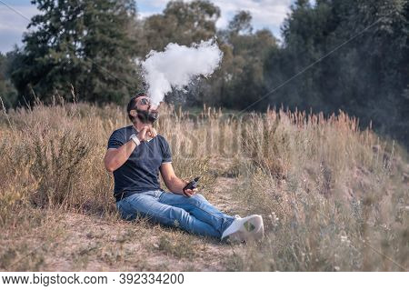Stylish Smoker Blowing A Lot Of Smoke Using Vape Vape. Electronic Cigarette As Alternative To Tobacc