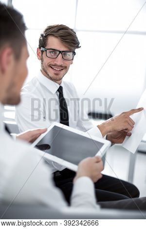 Team of two businessmen discussing new project using tablet and dokuments in the office.