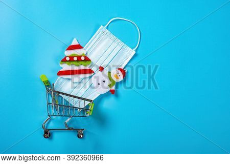 Shopping Cart With Medical Mask And Christmas Decorations On Blue Background