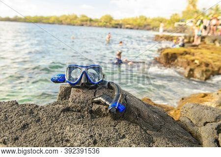 A Colorful Snorkle Or Diving Mask Located On The Rocks With Snorkling Group On The Back