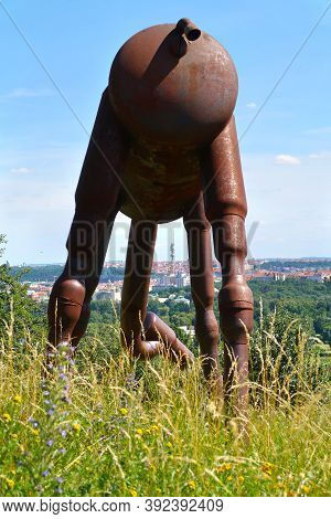 Metal Statue Of Camel In The Prague Botanical Garden With The View Of The Prague Cityscape In The Di