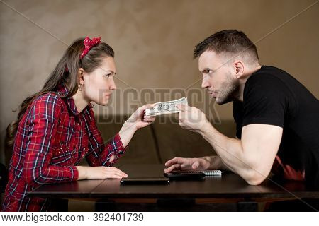 Husband And Wife Are Pulling Money At Each Other, Angrily Looking. Image Of Embittered Spouses Pulli