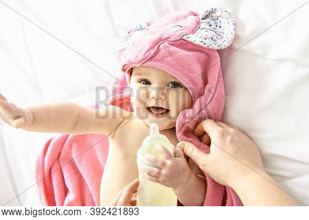 A Cute Happy Laughing Baby In Soft Bathrobe After Bath Playing On White Bed In Pink