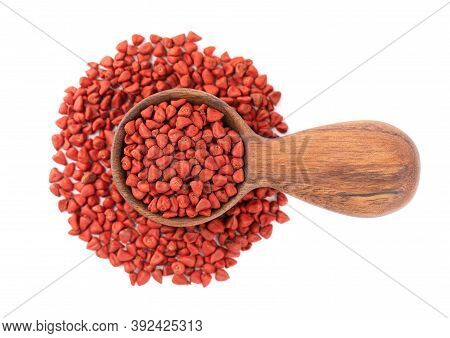 Annatto Seeds In Wooden Spoon, Isolated On White Background. Achiote Seeds, Bixa Orellana. Natural D