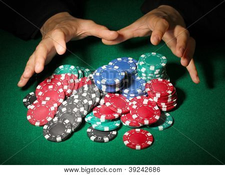 Poker fişleri ve yeşil masa üstündeki elleri
