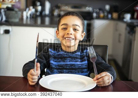 Boy Sitting At The Kitchen Table With Empty Plate