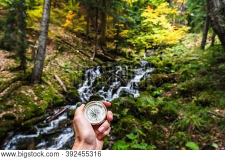 First-person View Of A Female Hand With A Compass On A Background Of A Beautiful Mountain Landscape.