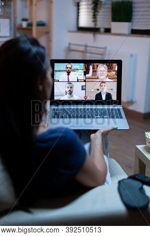 Freelancer Listening Online Training On Laptop At Night Sitting On Comfortable Couch. Remote Worker 