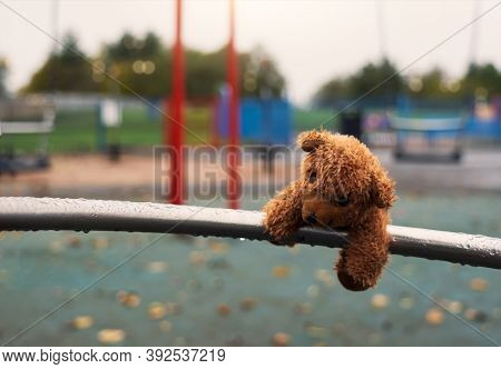Lost Teddy Bear Doll Lying On Metal With Rain Drops At Playground In Gloomy Day, Lonely Or Sad Brown