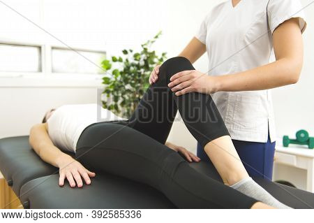 A Modern Rehabilitation Physiotherapist At Work With Client. Working On Knee