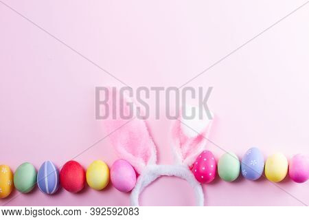 Easter Rabbit Flaffy Ears And Colored Easter Colored Eggs On Pink Background With Copy Space
