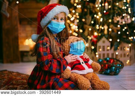 Portrait Of Cutel Little Child Girl In Medical Mask Playing With Taddy Bear, New Year Holiday Concep