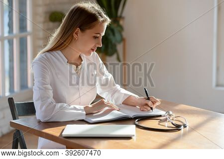 Responsible Concentrated Millennial Woman Therapist Making Recordings To Paper Casebook