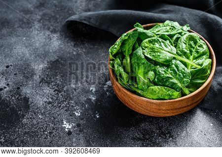 Young Raw Spinach In A Wooden Bowl. Black Background. Top View. Copy Space