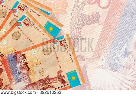 5000 Kazakhstani Tenge Bills Lies In Stack On Background Of Big Semi-transparent Banknote. Abstract 