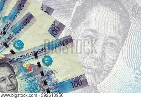 100 Philippine Piso Bills Lies In Stack On Background Of Big Semi-transparent Banknote. Abstract Bus