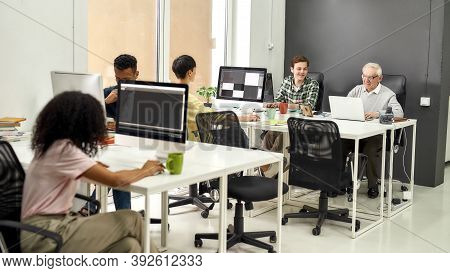 Full Length Shot Of Aged Man, Senior Intern Typing, Using Laptop While Sitting At Desk, Working Toge
