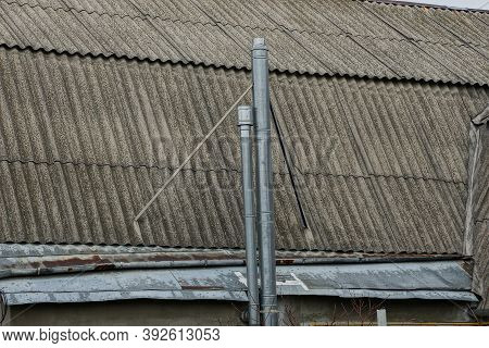 Two Long Gray Metal Chimney Pipes On The Slate Roof Of A Private House On The Street