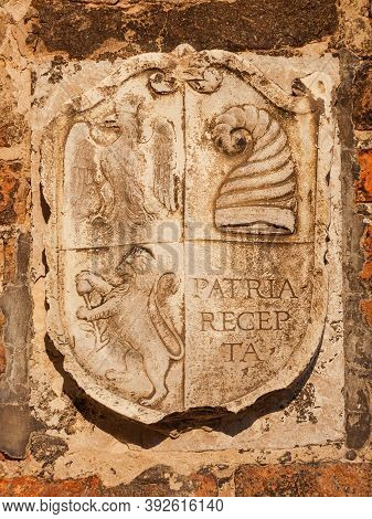 Old Heraldic Emblem With Imperial Eagle, Doge's Hat (horn) And Lion On A Venice Bricl Wall