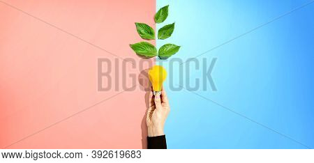 Person Holding A Light Bulbs With Green Leaves
