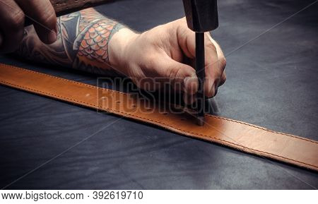Professional Tanner Cutting Out Leather Shapes For A New Product At The Workshelf