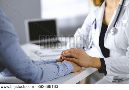 Unknown Woman-doctor Is Holding Her Patients Hands, Discussing Current Health Examination, While The