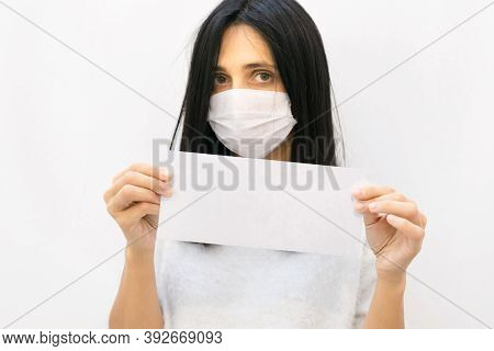 Close Up Of Young Caucasian Woman With White Mask On Holding White Envelope With Blank Space And Whi