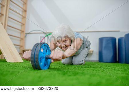 Grey-haired Elderly Woman Exercising In A Rehabilitation Center