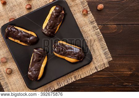 Eclairs With Black Chocolate And White Chocolate With Custard In Plate On Wooden Table. Traditional 