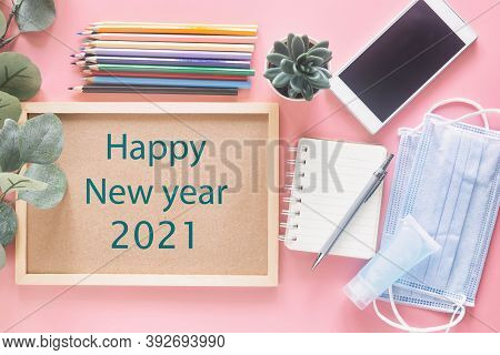 Happy New Year 2021 On Wooden Letter Board With Stationery, Smartphone, Mask And Hand Sanitizer On P