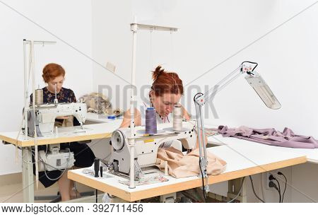 Two Caucasian Women Seamstress At Work On Sewing Machines In A Sewing Studio