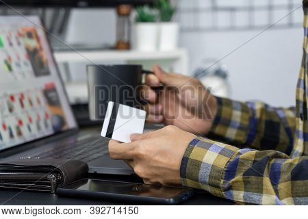 Asian Man Holding Credit Card And Typing Information On Internet With Laptop At Home, Online Shoppin