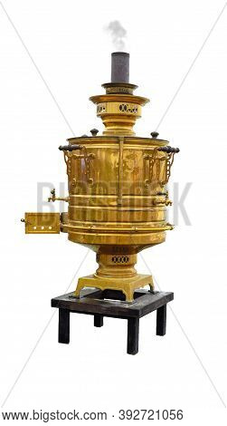 An Old Copper Samovar With A Chimney From Which Smoke Comes Stands On A Small Table Isolated On A Wh