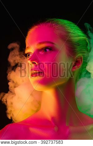 Mavelous. Portrait Of Female Fashion Model In Neon Light On Dark Studio Background With Smoke. Beaut