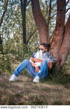 Confident Smoker Enjoying An Electronic Smoke Device In The Calm Outdoors. Hybrid Cigarette.