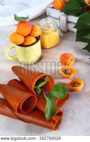 Apricot Pastille Rolled Into A Tube On A White Background. Apricots In A White Wooden Box And A Cera