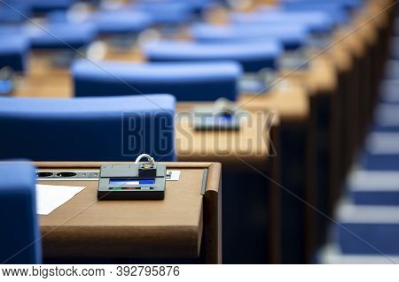 Inside Of An Empty Parliament Hall. Blue Chairs In Line With Voting Machines For Every Seat On The D