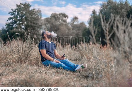 Stylish Smoker In The Fresh Air Smoking An Electronic Cigarette. Health Concept.
