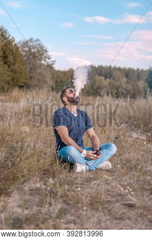 Stylish Vape Man Enjoying An Electronic Cigarette Outside. The New Technology Cigarette.