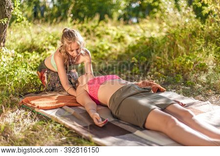 Massage Trainer Applies Her Massage Skills On Her Client On The Grass.