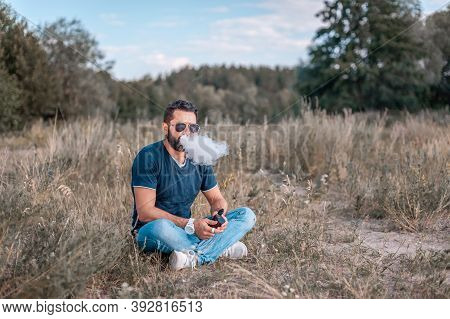Brutal Man Blowing A Lot Of Smoke Using Vape Electronic Smoke Device. Hybrid Cigarette.