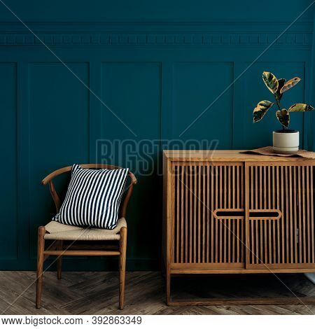 Scandinavian vintage wood cabinet with chair by a dark blue wall