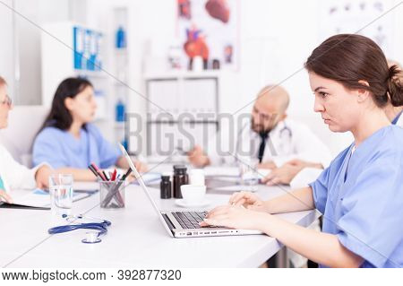 Medical Practitoner Working On Laptop During Briefing With Coworkers. Clinic Expert Therapist Talkin