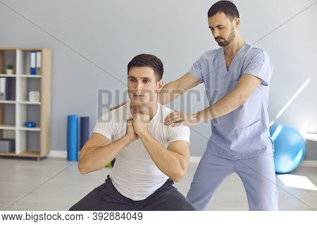 Physiotherapist Helping Young Athlete Do Squats During Rehabilitation Therapy After Sports Injury