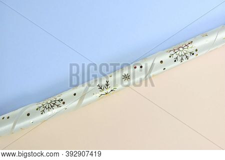White Spiral Ribbon  With Gold Christmas Pattern, Gold Snowflakes. Pastel Blue And Beige Background.